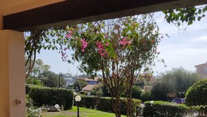Eine Terrasse mit Tisch und Stühlen, umgeben von Grünpflanzen und Blick auf die Nachbarschaft.