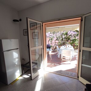 A kitchen with a refrigerator, a glass door leading to an outdoor patio with a table and chairs. - San Lorenzo House With Garden In Budoni (San Lorenzo)