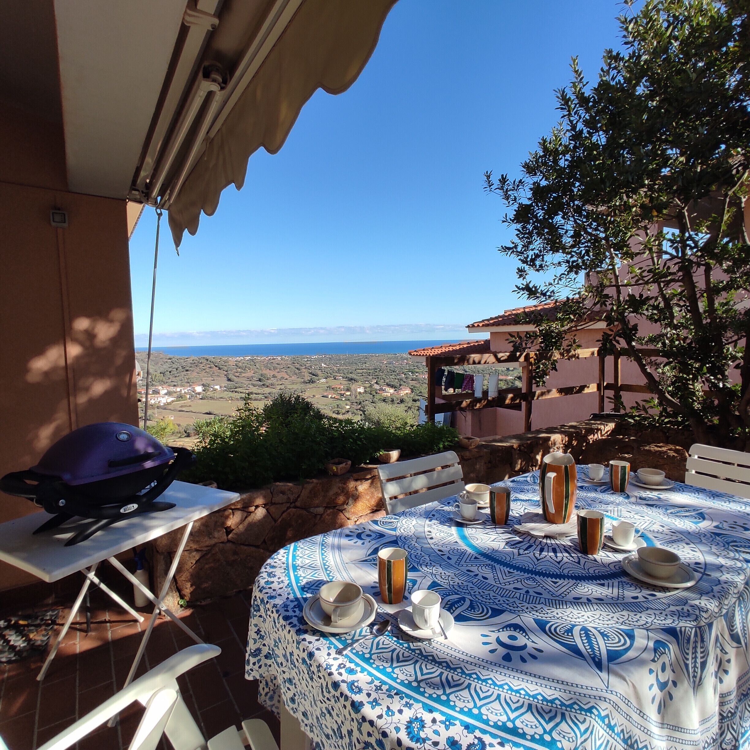 Een terras met een eettafel, een barbecue en uitzicht op het landschap.