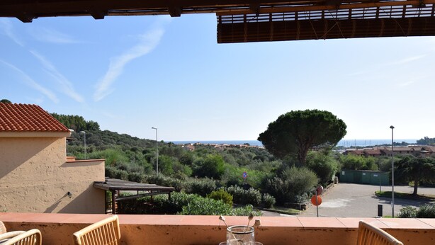 Ein Balkon mit Esstisch, der auf eine reizvolle Landschaft mit Bäumen und Gebäuden blickt.
