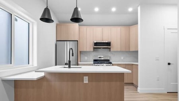 A modern kitchen with a central island, stainless steel appliances, and pendant lighting. - "Avanta" with free parking near UofC (Calgary)