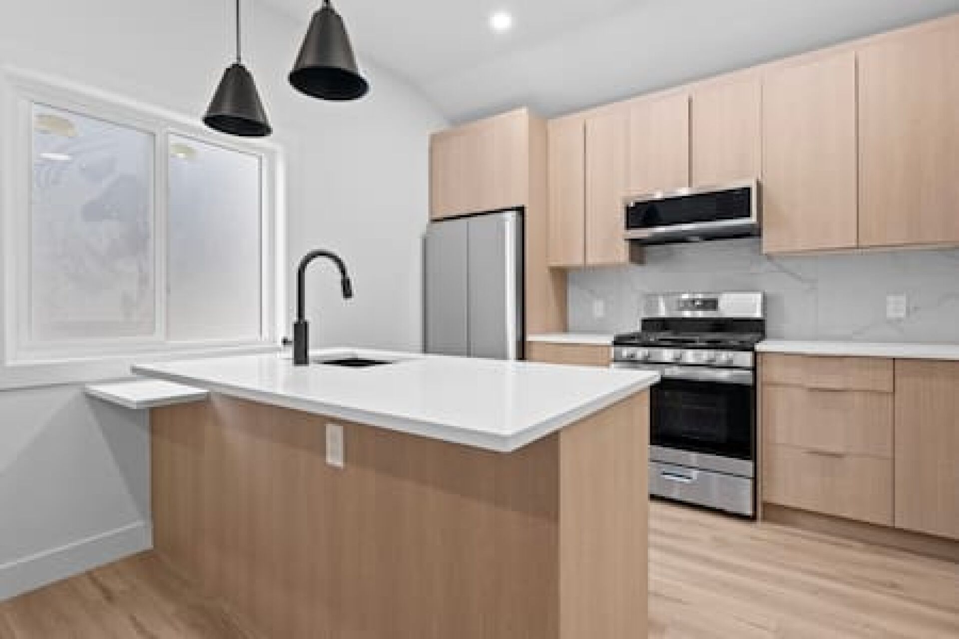 A modern kitchen with a central island, stainless steel appliances, and wooden cabinets.