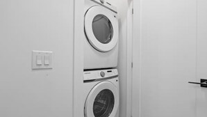 A laundry room with two stacked washing machines and a door. - "Avanta" with free parking near UofC (Calgary)
