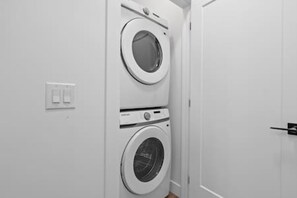 Una sala de bugaderia amb dues rentadores superposades i una porta.