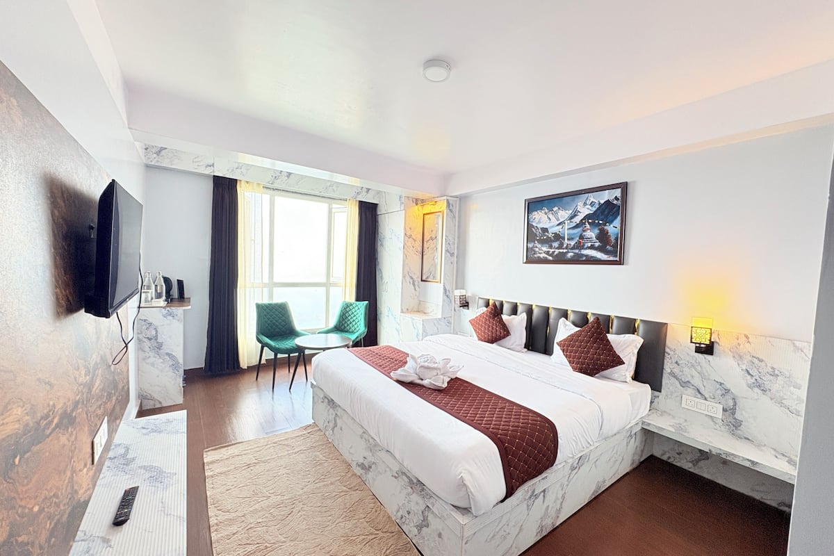 Quarto de hotel com uma cama, televisão, escrivaninha, cadeira e janela.