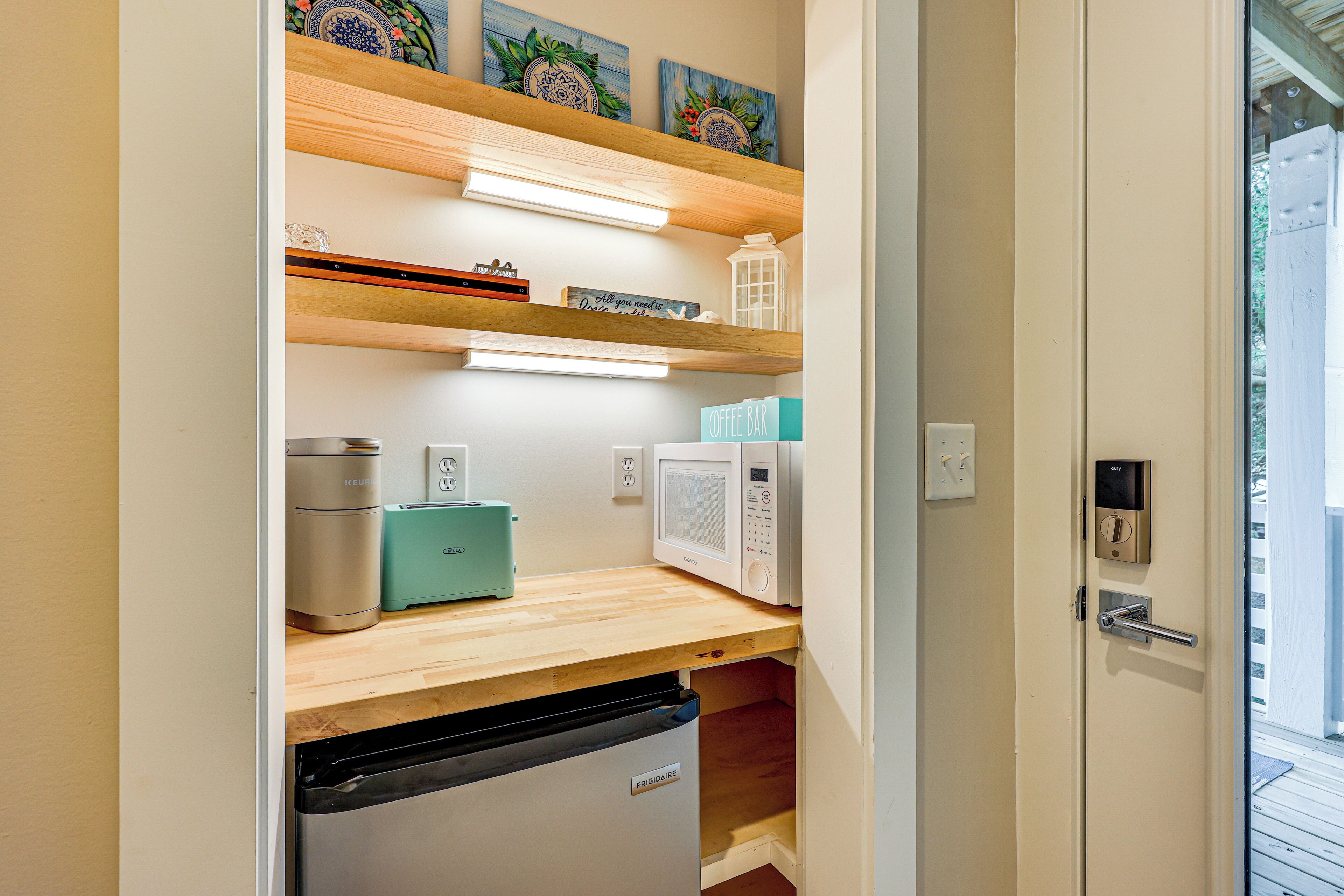 Una cocina compacta con lavavajillas integrado, microondas y cafetera sobre una encimera de madera.