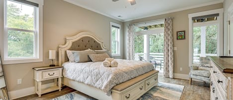 A bedroom with a large bed, a ceiling fan, and a view of the outdoors.