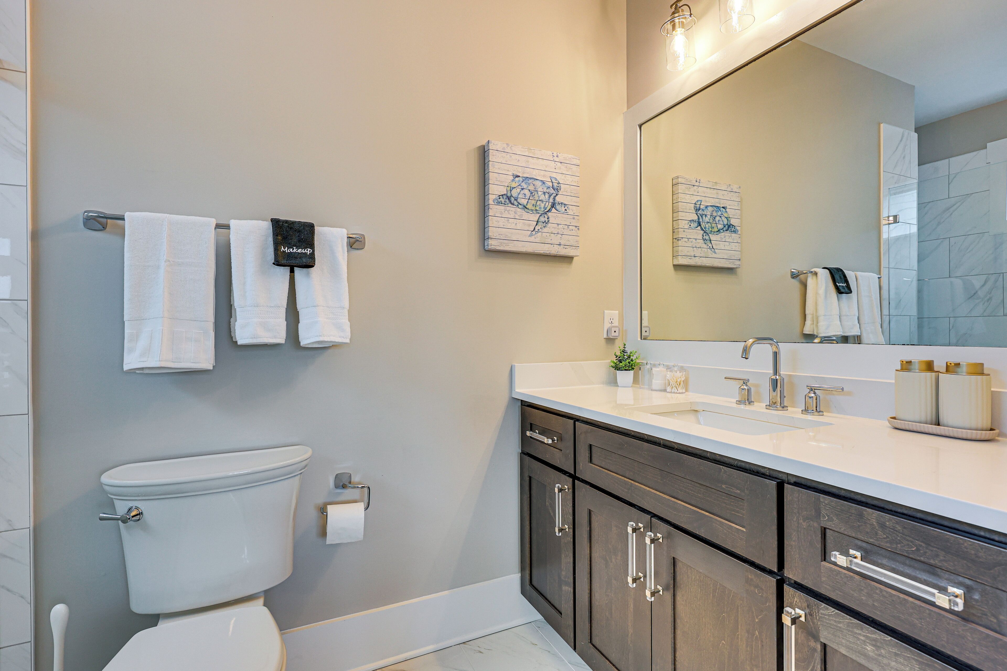 Een moderne badkamer met toilet, wastafel en donkere houten kastjes.