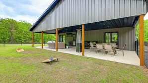 Een modern gebouw met een overdekte patio, buitenzitplaatsen en een barbecue.