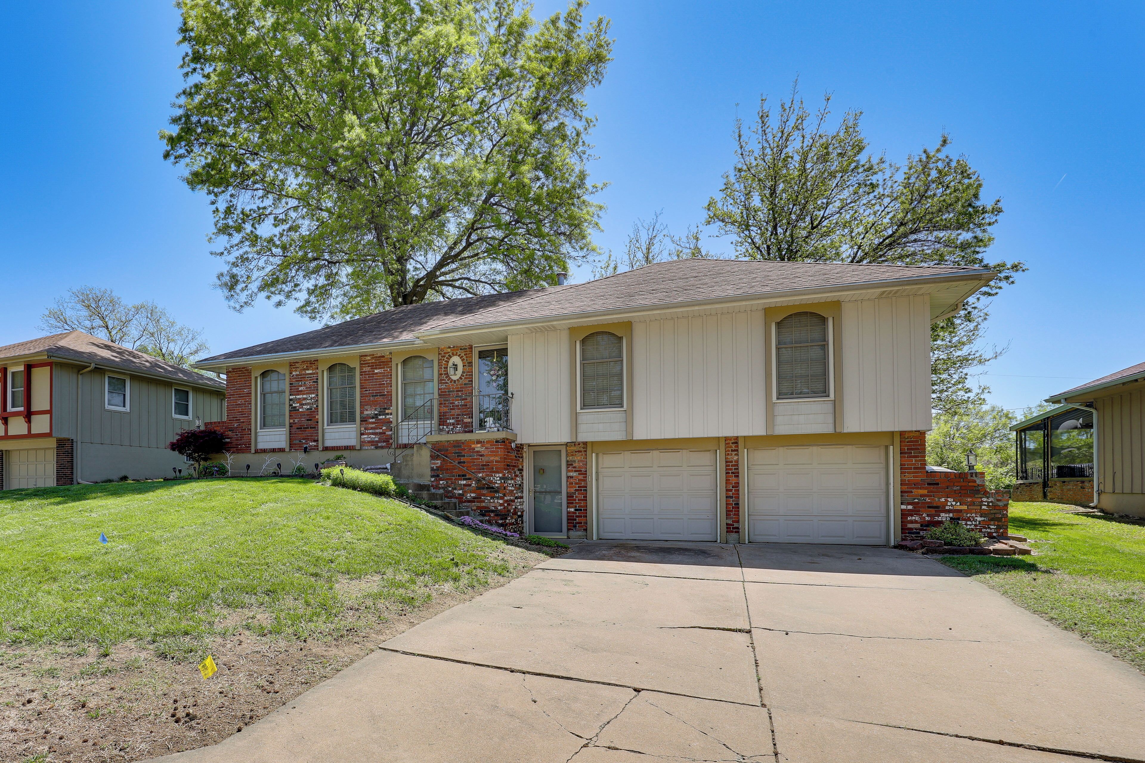 A two-story house with a garage, a front yard, and a large tree.