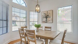 A dining room with a wooden table and chairs, a vase with flowers, and a painting on the wall. - Recently Remodeled Avondale Retreat, Private Yard! (Avondale)