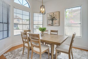 Un comedor con una mesa y sillas de madera, un florero con flores y un cuadro en la pared.