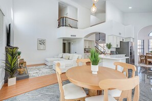 Ein großzügiger Wohnbereich mit Esstisch, Sofas und einer Küche im Hintergrund.