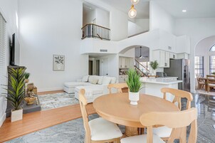 Amplia sala de estar con una mesa de comedor, sofás y una cocina al fondo.