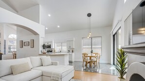 A modern living room with a sectional sofa, a dining area with wooden chairs, a kitchen in the background, and a fireplace. - Recently Remodeled Avondale Retreat, Private Yard! (Avondale)