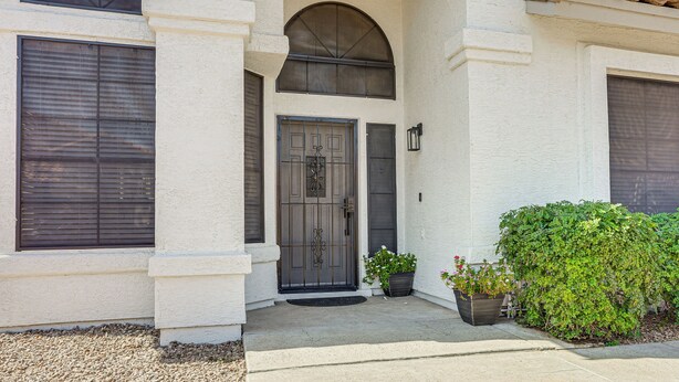 A building with a white exterior, a dark entrance door, and a small porch area with potted plants. - Recently Remodeled Avondale Retreat, Private Yard! (Avondale)
