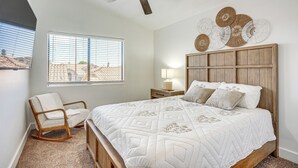 A bedroom with a bed, a rocking chair, a ceiling fan, a window with blinds, and wall decor. - Recently Remodeled Avondale Retreat, Private Yard! (Avondale)