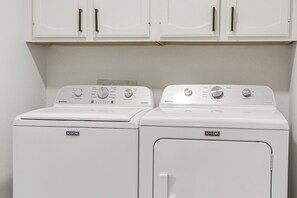 Dos lavadoras Maytag en un cuarto de lavado con gabinetes blancos arriba.