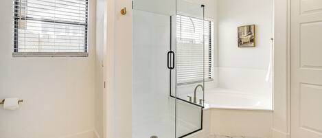 A bathroom with a glass-enclosed shower, a bathtub, and a toilet.