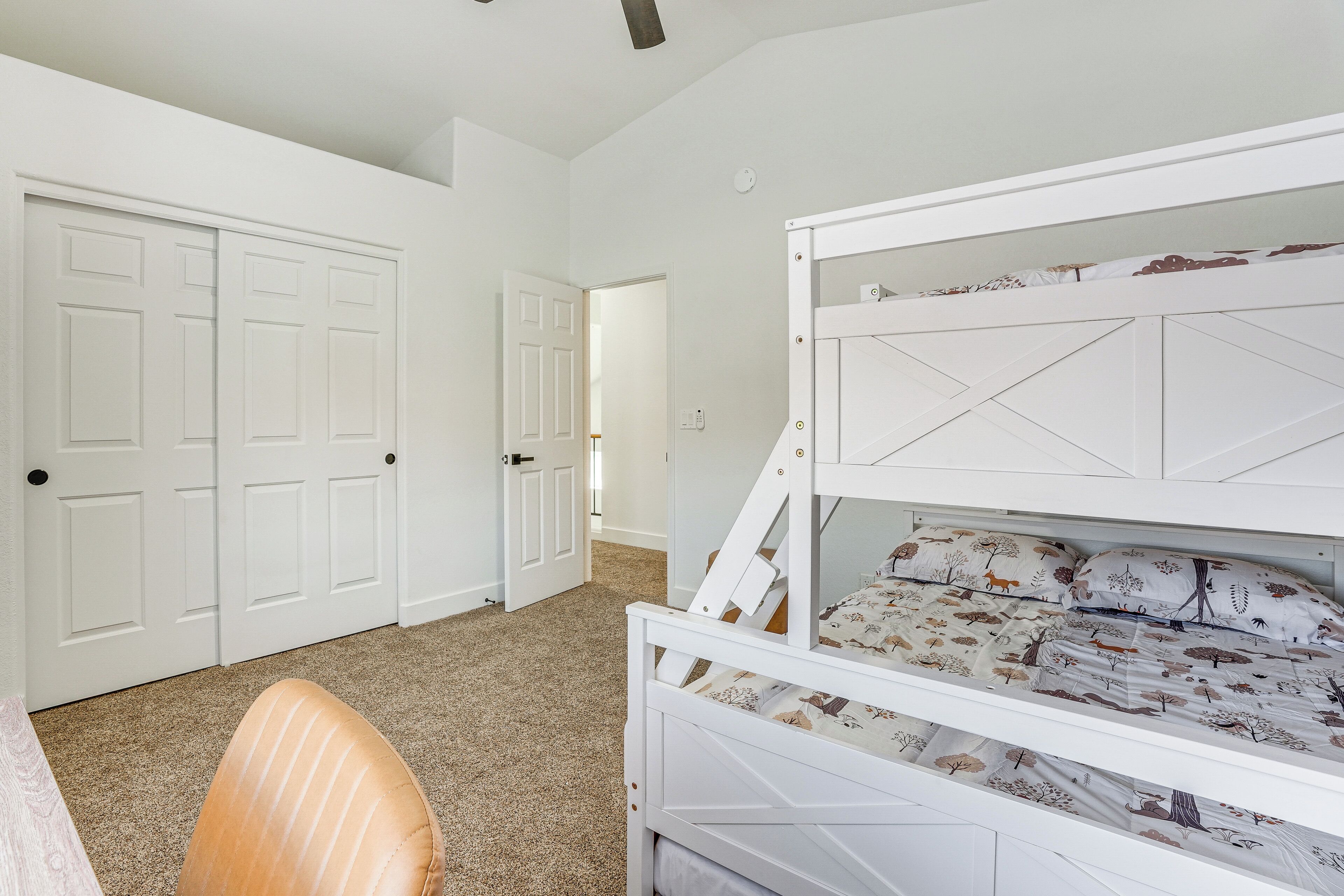 A bedroom with a bunk bed, carpeted floor, white walls, and a door.