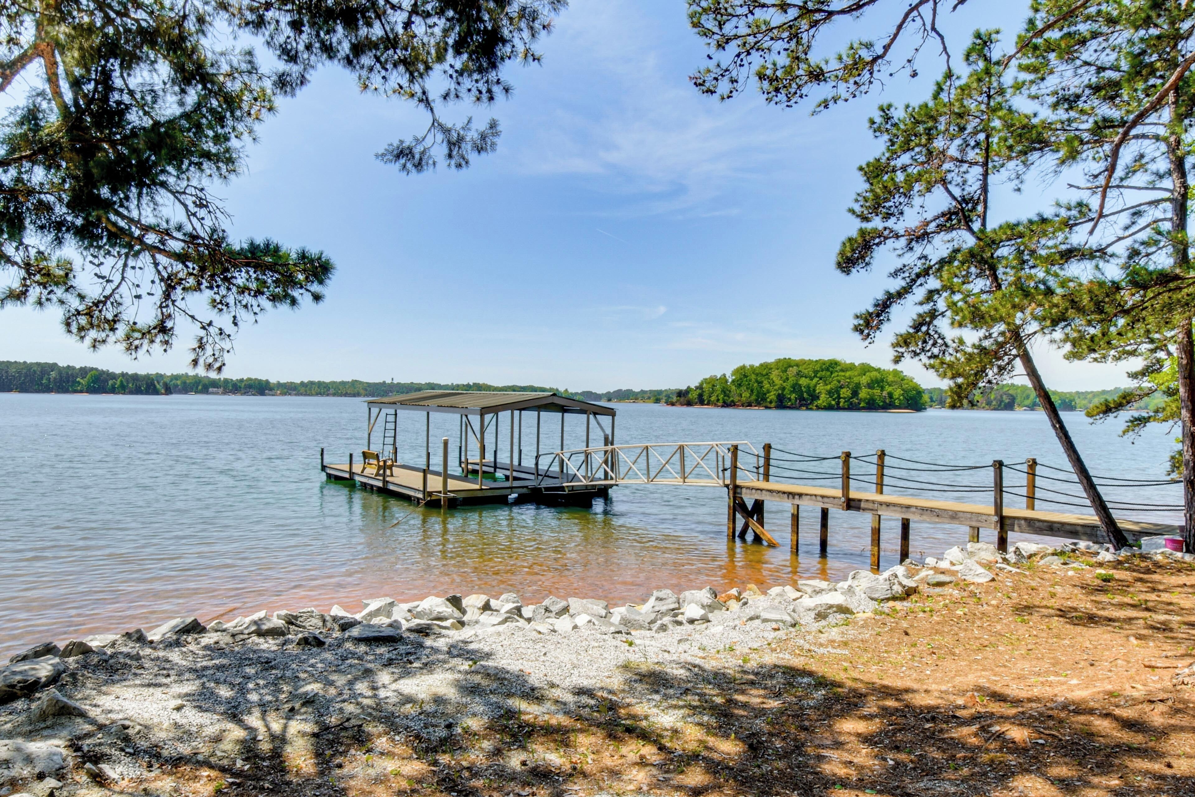 A lake with a dock, a covered structure, and a rocky shoreline.