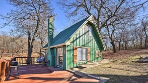 A green house with a wooden deck, a chimney, and a large window. - Hot Tub, Pool, Dock: 2 Cabins Lakeview Grand Lake (Grove)