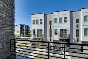 A modern residential building with a balcony, a clear sky, and a gravel driveway. - Rooftop Oasis: Downtown Des Moines Townhome (Des Moines)
