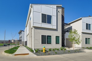 A modern two-story residential building with a garage, a fire hydrant, and a landscaped area with small plants. - Rooftop Oasis: Downtown Des Moines Townhome (Des Moines)