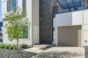 A modern two-story house with a garage, a small tree, and a stone wall. - Rooftop Oasis: Downtown Des Moines Townhome (Des Moines)