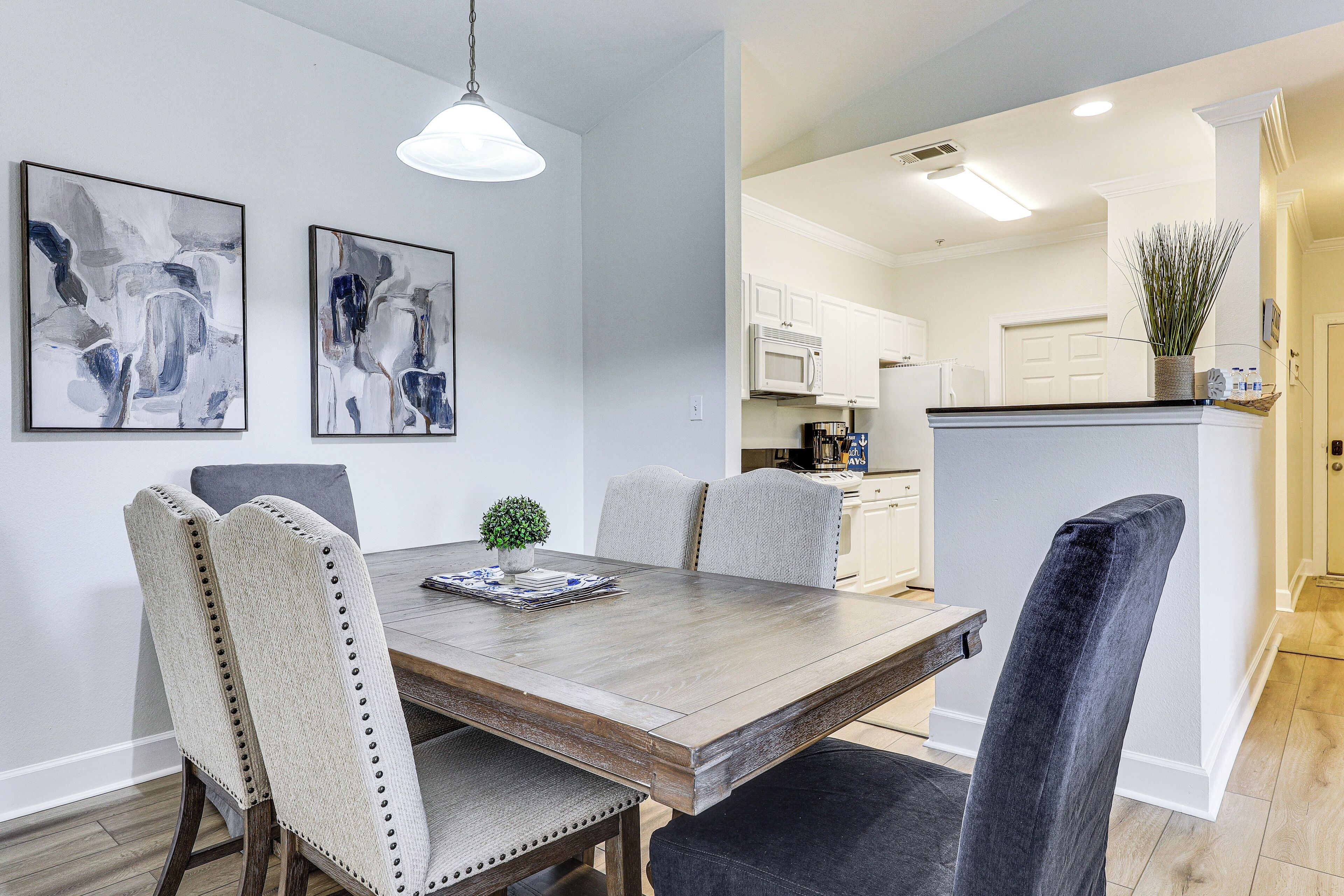 A dining area with a wooden table, upholstered chairs, and abstract wall art.