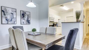 A dining area with a wooden table, upholstered chairs, and abstract wall art.