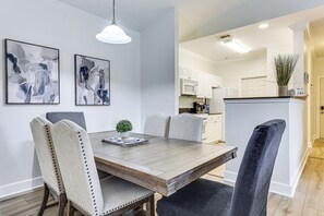 A dining area with a wooden table, upholstered chairs, and abstract wall art.