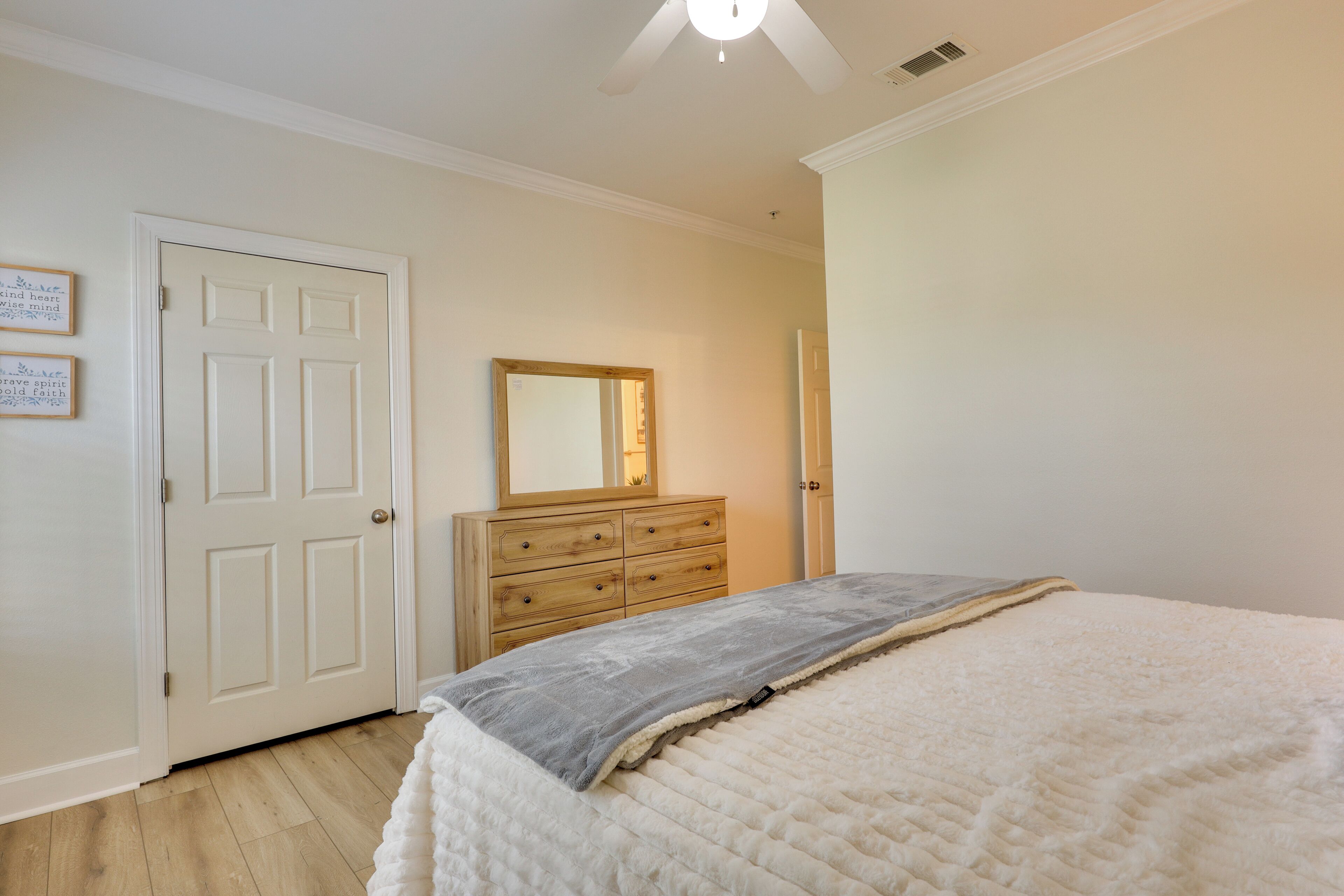 A bedroom with a bed, a dresser, a mirror, and a door.