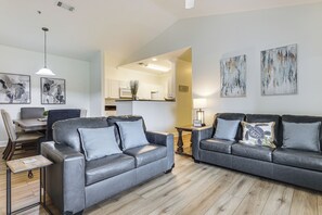 A modern living room with two grey leather sofas, a dining table, and artwork on the walls. - Pool Access! Recently Updated Coastal Retreat (Foley)