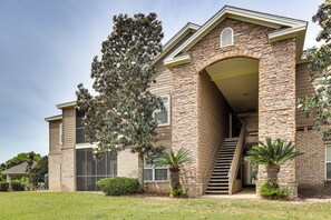 A two-story house with a stone facade, a covered porch, and a staircase leading to the upper level. - Pool Access! Recently Updated Coastal Retreat (Foley)