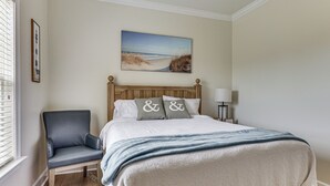 Quarto com cama, cadeira, quadro e abajur.