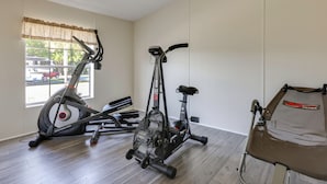 A room with two stationary bikes, a bench, and a window with a view of parked cars and trees. - Pool Access! Spacious Home Near Wekiwa Springs (Apopka)
