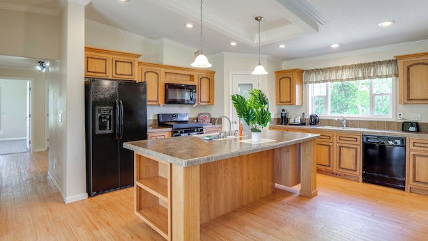 A modern kitchen with wooden cabinets, a central island, stainless steel appliances, and pendant lighting. - Pool Access! Spacious Home Near Wekiwa Springs (Apopka)