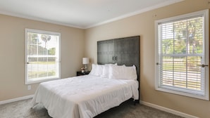 A bedroom with a bed, a nightstand, a lamp, and a headboard. - Pool Access! Spacious Home Near Wekiwa Springs (Apopka)