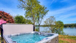 Un jacuzzi con tapa, rodeado de árboles y vistas al lago.