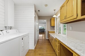 A laundry area with a washing machine, wooden cabinets, and a marble countertop. - Serenity Dock on Watts Bar Lake- Main Channel View (Harriman)