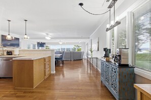 A modern kitchen with wooden cabinetry, a central island, pendant lighting, and a view through large windows. - Serenity Dock on Watts Bar Lake- Main Channel View (Harriman)