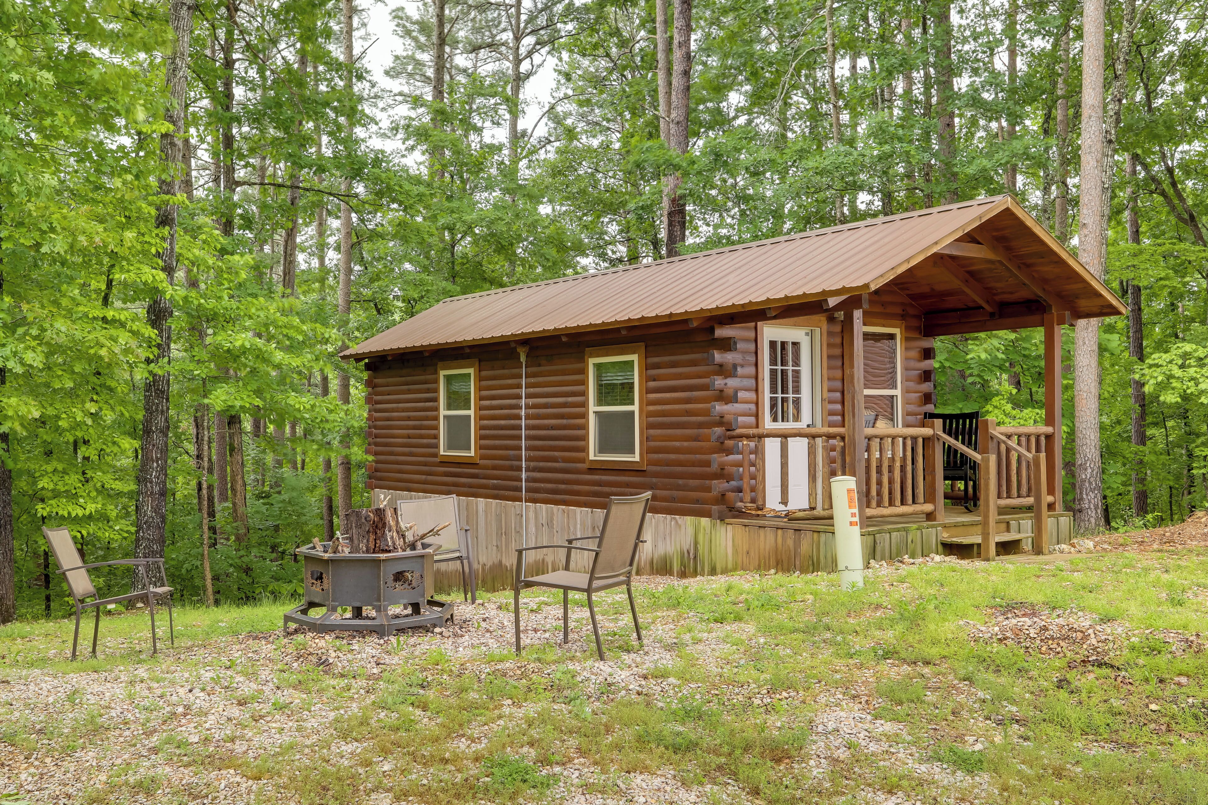 A log cabin with a porch, a fire pit, and a chair.
