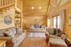 Interior acogedor de una cabaña con paredes de madera, un sofá, un sillón y un comedor.