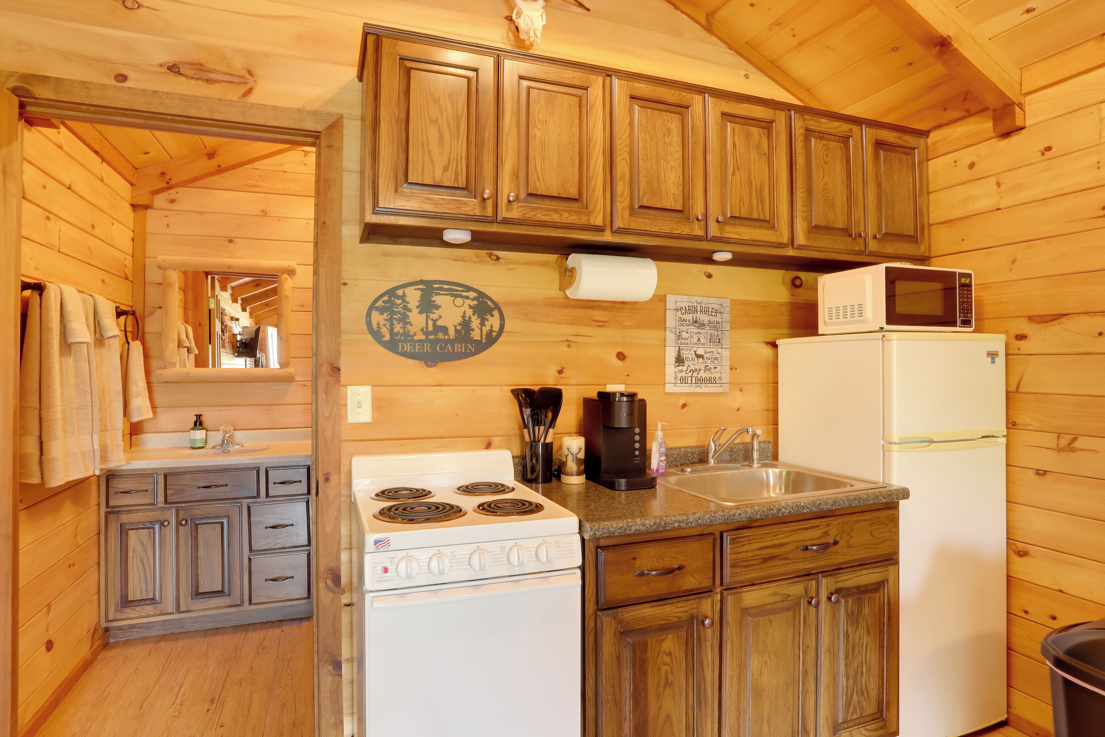 Une cuisine de style rustique, avec des meubles en bois, une cuisinière, un réfrigérateur et un four à micro-ondes.