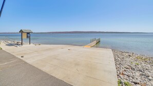 A concrete dock extending into calm water with a small shelter and a solar panel on the left. - Walk to the Beach! Boyne City Escape w/ Lake Views (Boyne City)