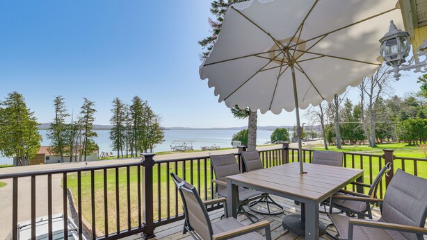 A deck with a table and chairs, overlooking a body of water. - Walk to the Beach! Boyne City Escape w/ Lake Views (Boyne City)
