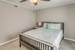 A bedroom with a bed, a nightstand, a ceiling fan, and a wall vent. - Walk to Ocean! Family Haven in North Myrtle Beach (North Myrtle Beach)