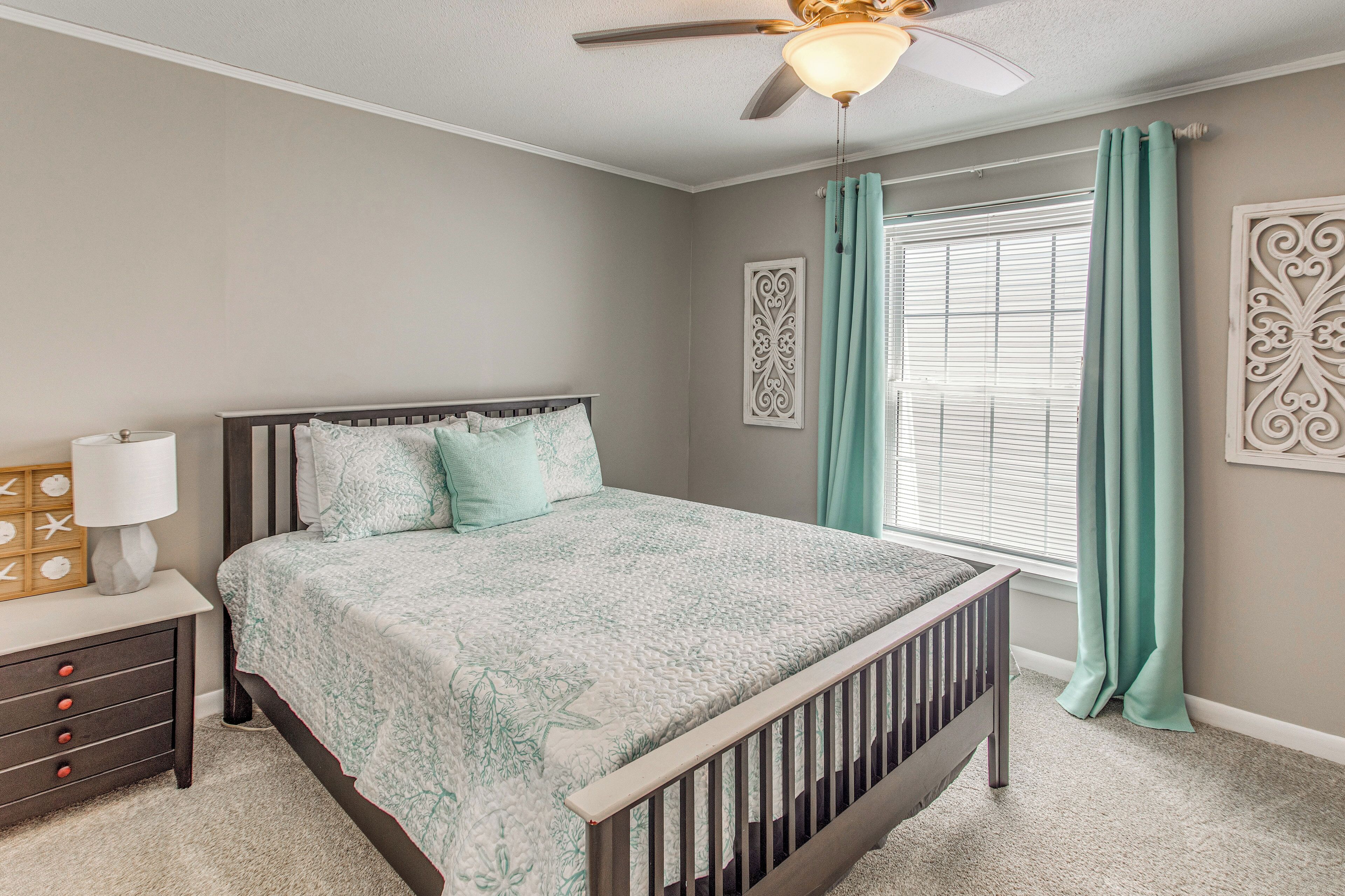 A bedroom with a bed, nightstand, and window with curtains.