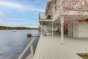 A waterfront property with a wooden deck, outdoor seating, and a view of the water.